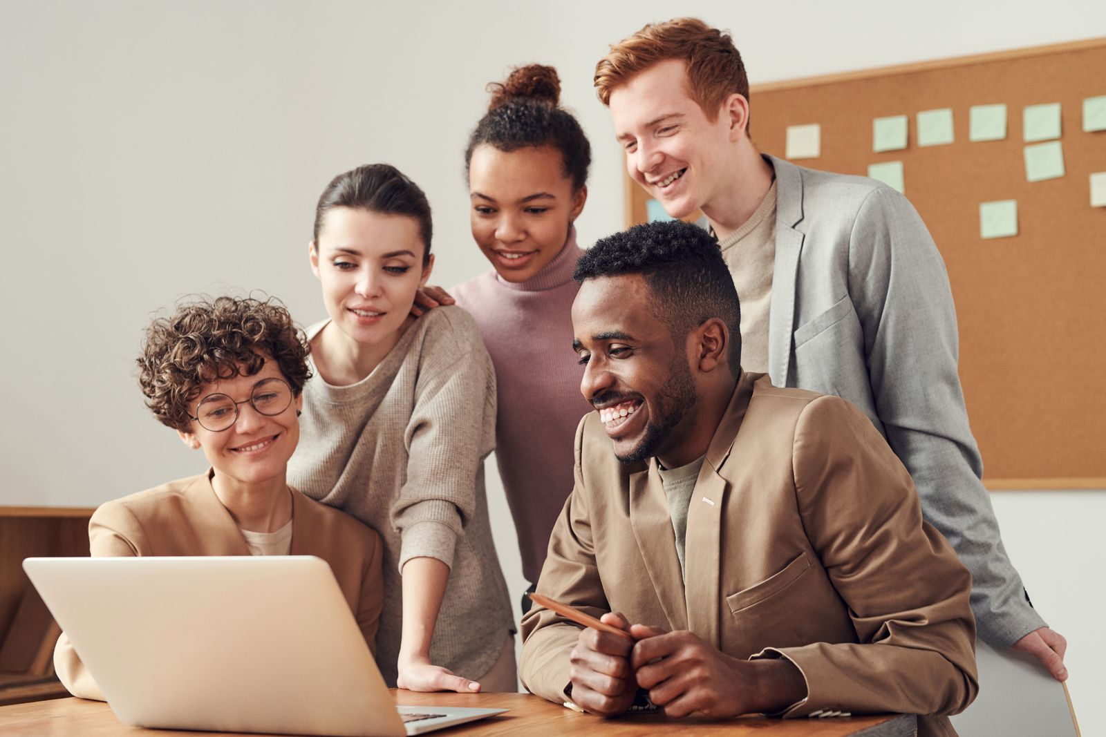 Smiling colleagues working together around a laptop in a bright office